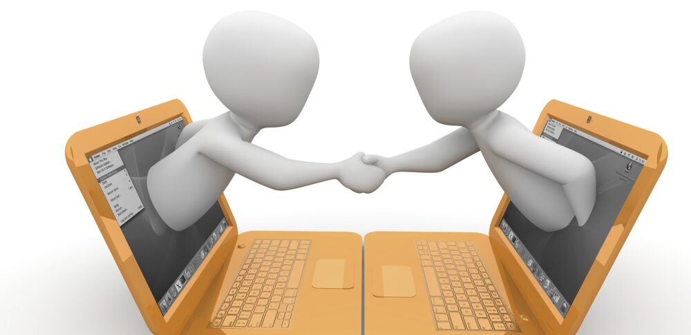 2 Laptops liegen gegenüber. 2 Männchen kommen aus dem Bildschirmen und geben sich die Hand.