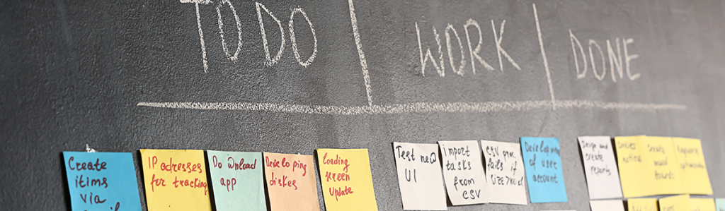 Bild von einer schwarzen Tafel mit Post-its organisiert in den Kategorien ToDo, Work und Done.